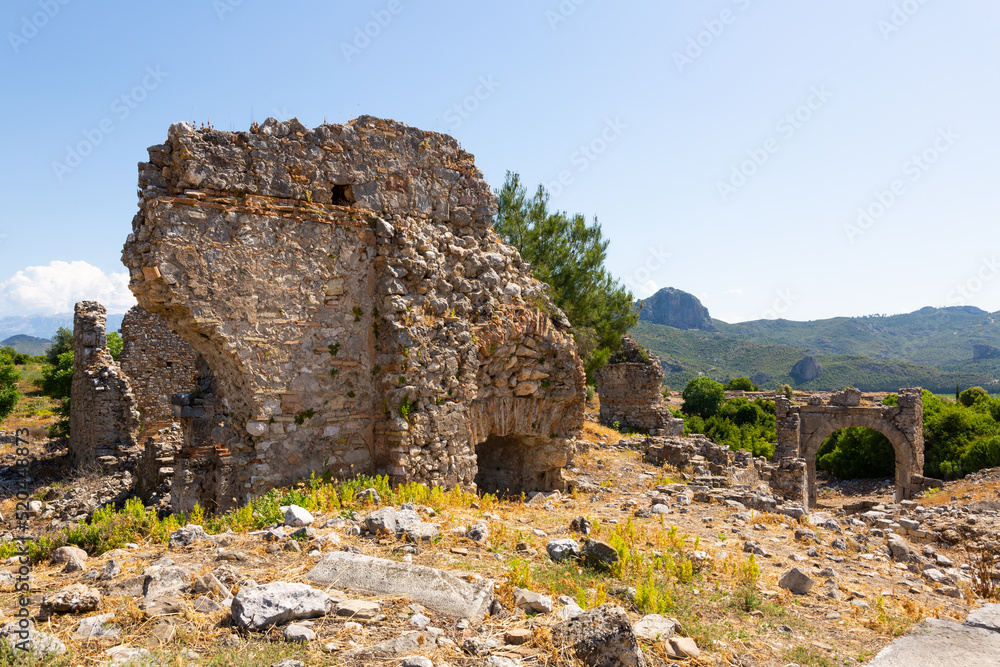 View of remains of buildings and eastern city gate over ancient road of Aspendos antique town, Turkey