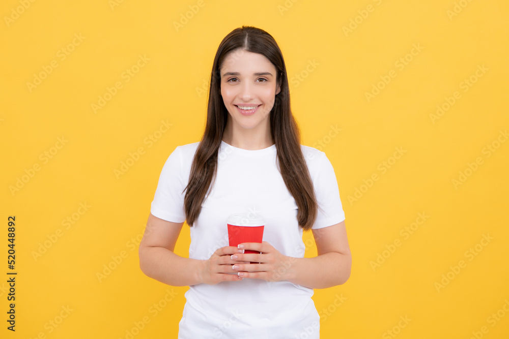 Close-up portrait of attractive dreamy girl holding in hands drinking latte isolated on yellow background. Young brunette woman drinking a cup of coffee. Close-up portrait of attractive dreamy girl holding in hands drinking latte isolated on yellow background. Young brunette woman drinking a cup of coffee.