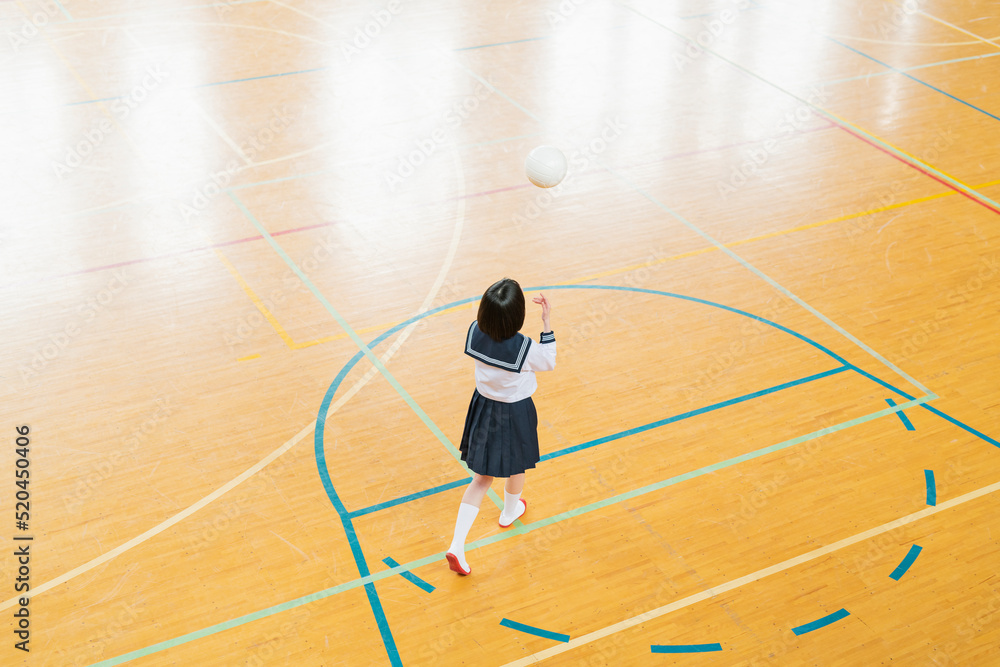 体育館でボール遊びをする女子高生