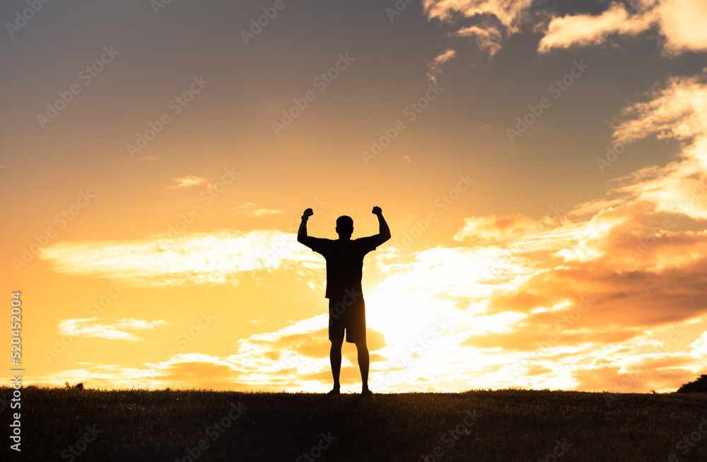Young strong man with arms flexed up to the sky feeling empowered, and determined.	