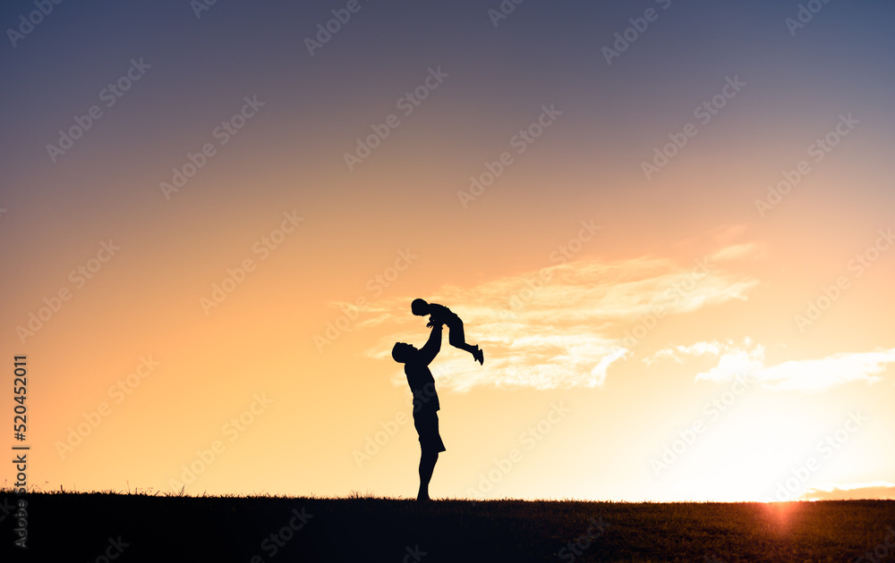 Young father holding his son up to the sunset sky. Fatherhood, and family lifestyle connect. 