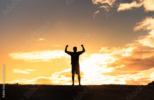 Young strong man with arms flexed up to the sky feeling empowered, and determined. 