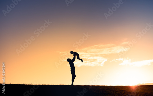 Young father holding his son up to the sunset sky. Fatherhood, and family lifestyle connect. 