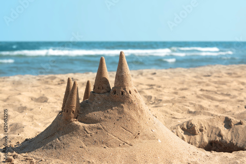 Beach with sand castle near sea on sunny day