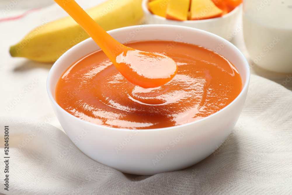 Spoon of healthy baby food over bowl on table, closeup Spoon of healthy baby food over bowl on table, closeup