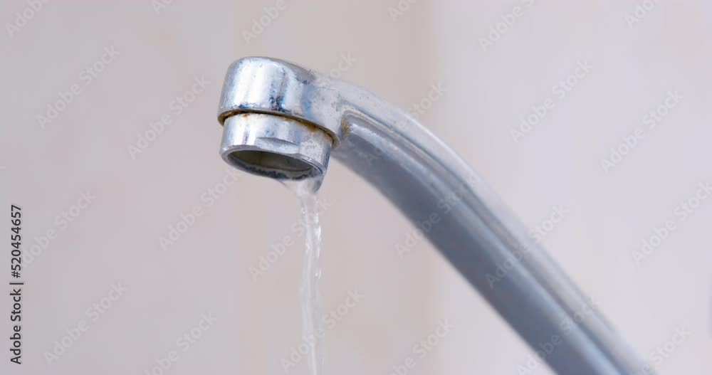 Weak stream of clean transparent water runs from broken grey metal faucet. Thin clean water stream flows slowly extreme closeup Weak stream of clean transparent water runs from broken grey metal faucet. Thin clean water stream flows slowly extreme closeup