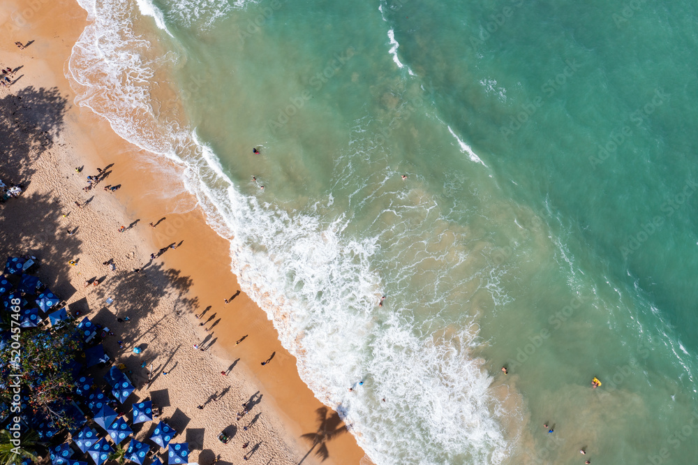 Imagem vista por cima da praia de Pitinga em Arraial da Ajuda, Porto Seguro, com alguns turistas e guarda-sóis sobre a areia próximos ás águas claras do Mar 