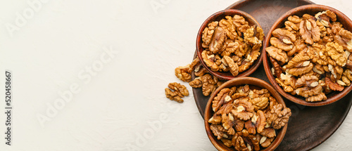 Bowls with tasty walnuts on white background with space for text, top view