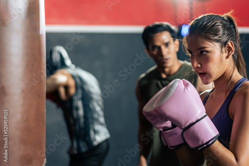 Group of athlete hitting a punching bag or sandbag at fitness gym club photo