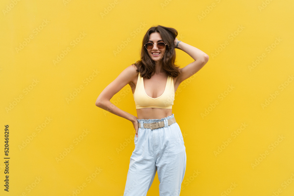 Young beautiful woman. Carefree woman posing in the street near yellow wall. Positive model outdoors in sunglasses. Happy and cheerful Young beautiful woman. Carefree woman posing in the street near yellow wall. Positive model outdoors in sunglasses. Happy and cheerful