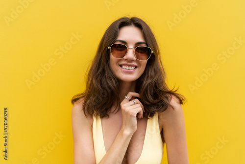 Young beautiful woman. Carefree woman posing in the street near yellow wall. Positive model outdoors in sunglasses. Happy and cheerful