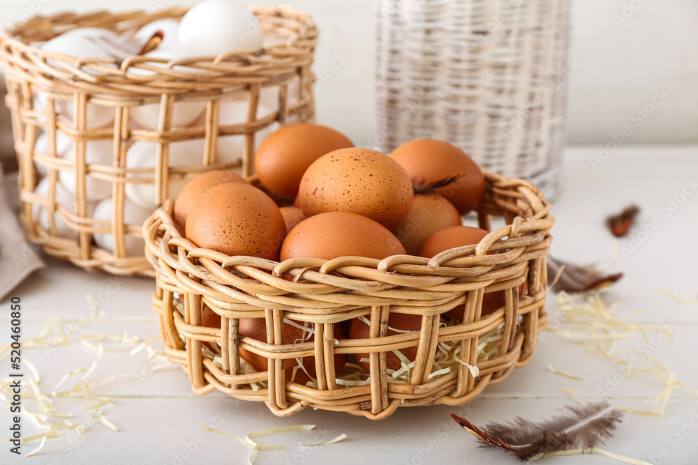 Wicker baskets with chicken eggs on white wooden table Wicker baskets with chicken eggs on white wooden table