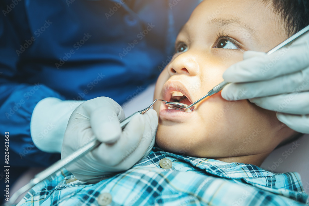 Dentist examines child's teeth using metal instruments at dental clinic. Dentistry and healthcare concept Dentist examines child's teeth using metal instruments at dental clinic. Dentistry and healthcare concept