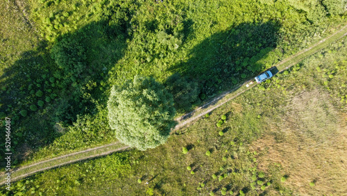 the car is driving along the road through the meadows and fields shooting from a drone, Ukraine