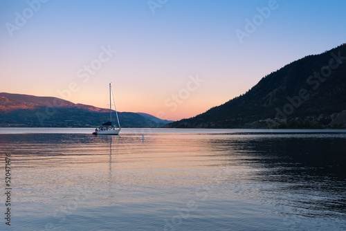 View of Okanagan Lake and sailboat at sunset in summer