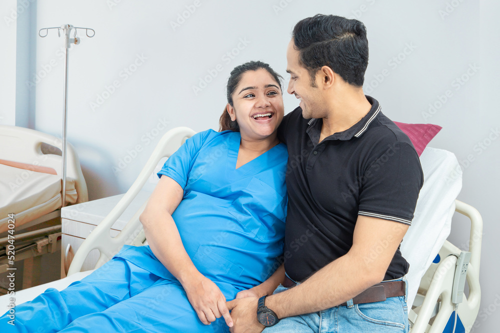 Happy young indian man hugging pregnant wife lying on bed in hospital, Smiling asian couple expecting baby. Happy young indian man hugging pregnant wife lying on bed in hospital, Smiling asian couple expecting baby.