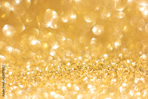 Defocused abstract colorful twinkle light background. Gold glittery bright shimmering background use as a design backdrop.