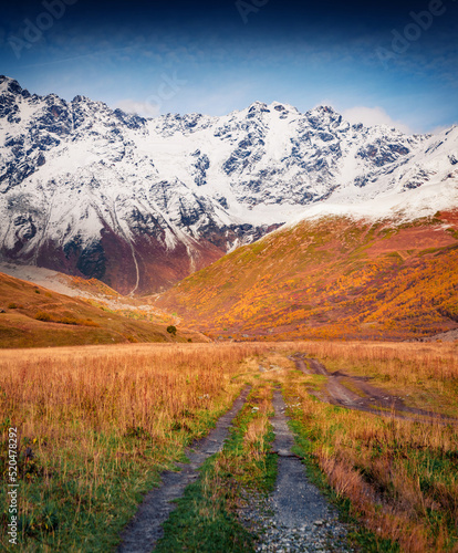 Country road in Caucasus mountains. Snowy peaks in Upper Svaneti. Adorable autumn scene in outskirts of Ushguli village, Georgia, Europe. Beauty of nature concept background..