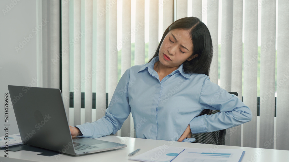 Asian woman who sits at work for a long time has back pain while massaging her hands. Asian woman who sits at work for a long time has back pain while massaging her hands.