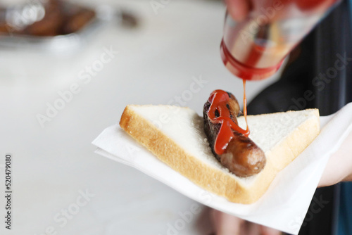 The humbe sausage sandwich or sausage in bread. Sang sanga. Traditional kids favorite at the bbq fundraiser with white bread and bright red tomato sauce or ketchup
