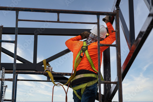 Industrial steel roof truss welders are welding steel with Fall arrestor device for worker with hooks for safety body harness on the construction site.