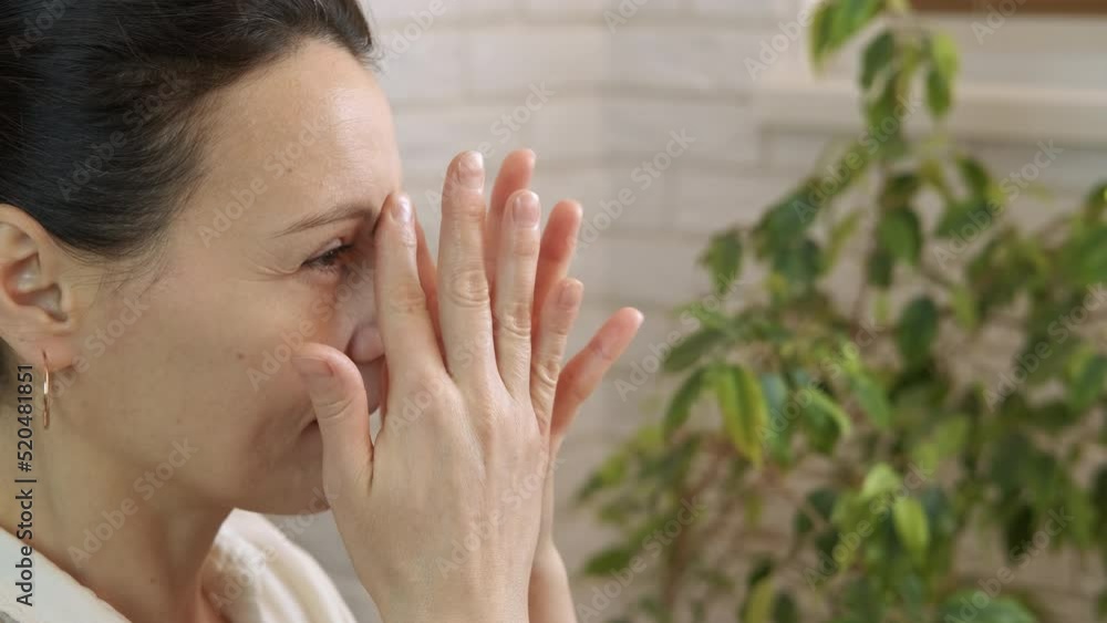Sinus massage in epidemic. A calm woman improve her breathing with a sinus massage on her face in the room. Sinus massage in epidemic. A calm woman improve her breathing with a sinus massage on her face in the room.