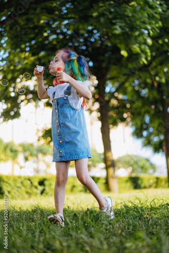 Cute caucasian girl having fun on girl birthday blowing bubbles in park