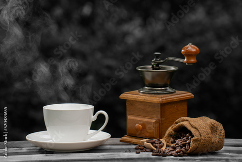 coffee cup with a grinder, Dark Coffee beans on the old wooden floor, Close up of seeds of coffee in a natural background.