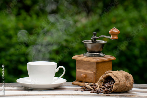 coffee cup with a grinder, Dark Coffee beans on the old wooden floor, Close up of seeds of coffee in a natural background.