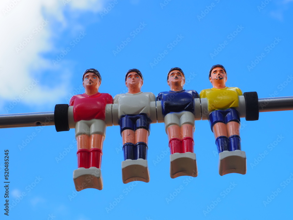 Obraz premium group of colored plastic foosball players on blue sky background