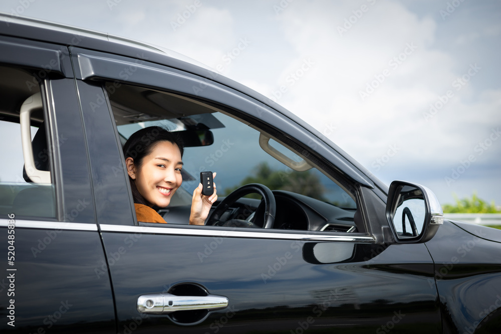 Young beautiful asian women getting new car. she very happy and excited looking outside window in hand holding car key. Smiling female driving vehicle on the road on a bright day Young beautiful asian women getting new car. she very happy and excited looking outside window in hand holding car key. Smiling female driving vehicle on the road on a bright day