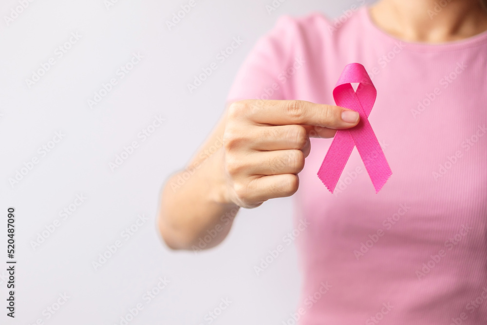 Fototapeta premium Pink October Breast Cancer Awareness month, woman hand hold pink Ribbon and wear shirt for support people life and illness. National cancer survivors month, Mother and World cancer day concept