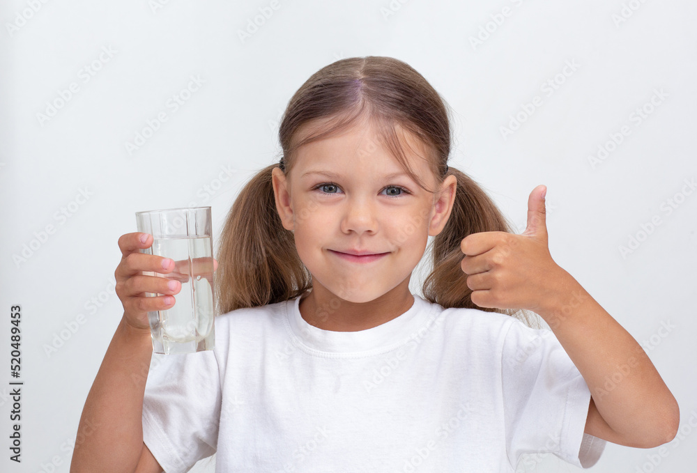 Caucasian beautiful child of 6 years holding glass of pure water looking at camera on white background Caucasian beautiful child of 6 years holding glass of pure water looking at camera on white background