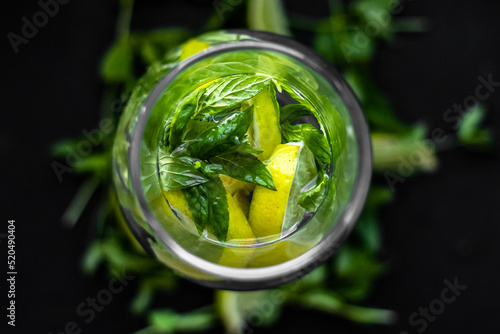 Lime slices and mint sprigs on a black background. Lime and mint. Summer freshness. Natural background. Ingredients of lemonade. Yellow and green colors in still life. A sprig of mint. Sliced lime.