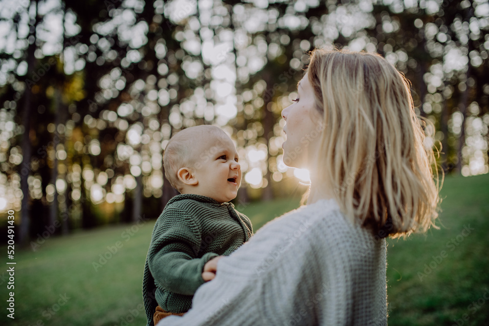 Mother holding her little baby son wearing knitted sweater during walk in nature, close-up Mother holding her little baby son wearing knitted sweater during walk in nature, close-up