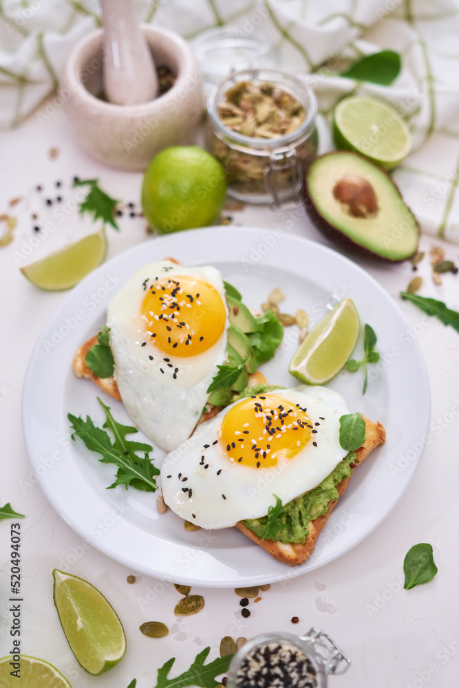 healthy breakfast or snack - sliced avocado and fried egg on toasted bread 