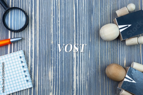 VOST - word (text) on a wooden background, notepad and pen with calculator. Business concept (copy space). photo