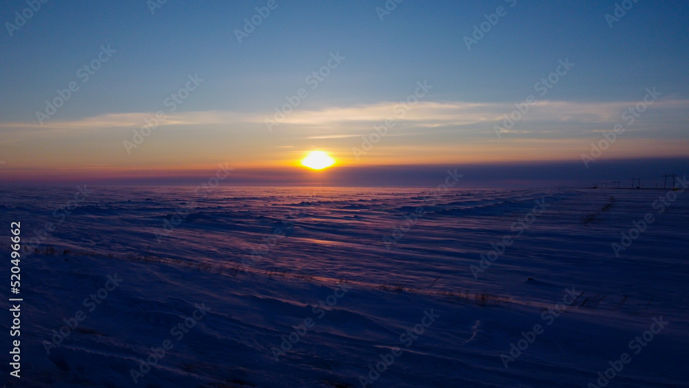 Beautiful sunset over a long field covered with snow