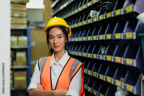 Portrait of female staff standing with arms crossed in warehouse, Industrial and industrial workers concept.
