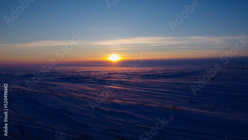 Beautiful sunset over a long field covered with snow