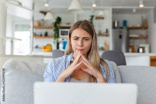 Confused businesswoman annoyed by online problem, spam email or fake internet news looking at laptop, female office worker feeling shocked about stuck computer, bewildered by scam message or virus