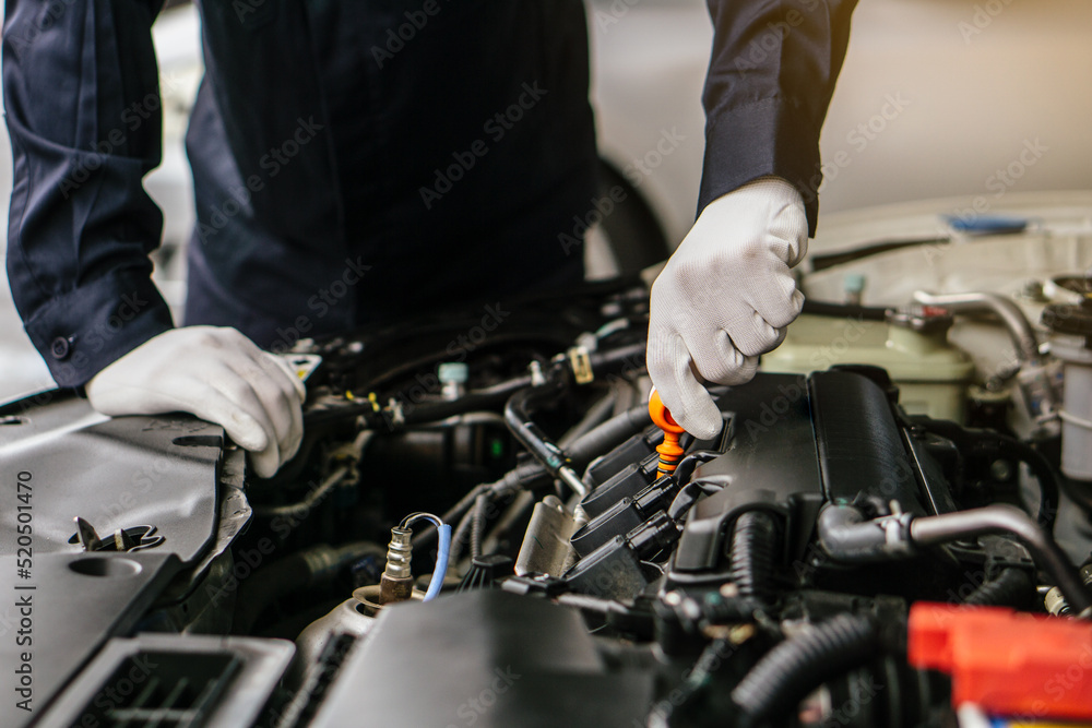Mechanic man working on the engine of the car in the garage.Car service and maintenance,Repair service.Checks car engine under the hood Mechanic man working on the engine of the car in the garage.Car service and maintenance,Repair service.Checks car engine under the hood