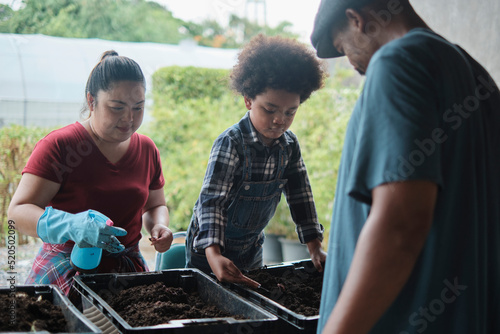 African American farmer family teaches son to prepare bio-fertilizer together by earthworm in the soil, biology and nature ecology learning, organic gardener hobby, childhood countryside agriculture.