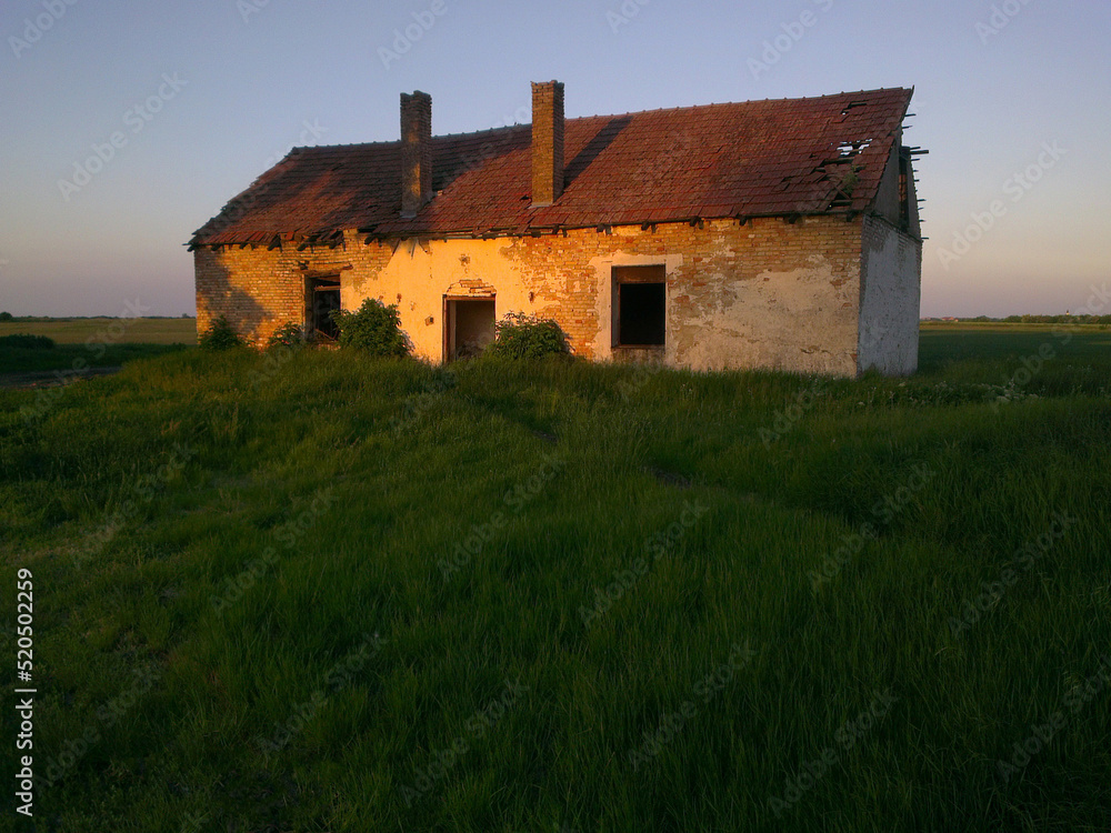 Abandoned farm house in the middle of the field at dusk