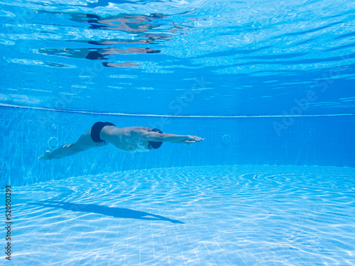 Wallpaper Mural Athlete swimmer breathing out air bubbles, while diving, training in the blue waters of a swimming pool. Selective focus. Underwater concept. Sport, recreation, lifestyle concept. Torontodigital.ca