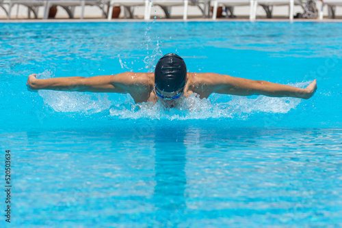 Close up action shot of athlete  young man  teenager swimming butterfly style. Sport  recreation concept.