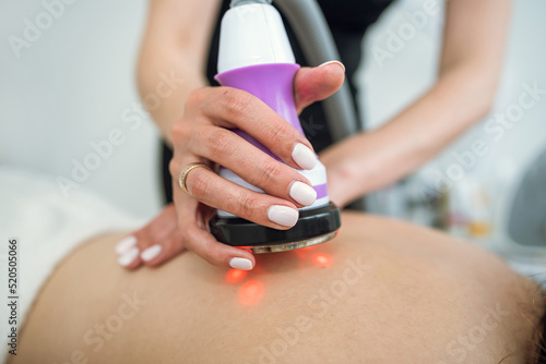 Beautiful woman receives  procedure removing cellulite on her back with vacuum massage device photo