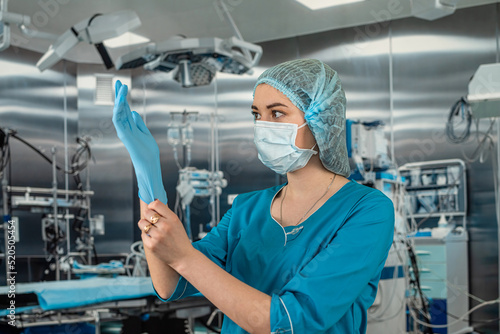 nurse wears uniform with while putting rubber latex gloves during complex surgical operation.