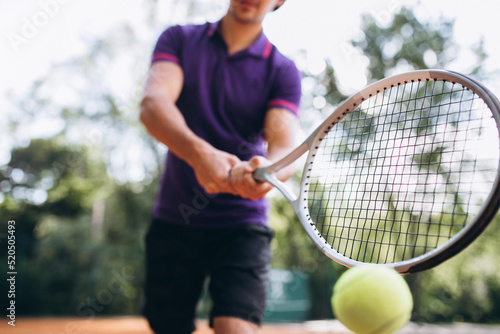 Young man tennis player at the court, tennis racket close up © Petro
