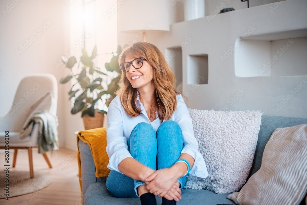 Happy middle aged woman relaxing on the sofa at home Happy middle aged woman relaxing on the sofa at home